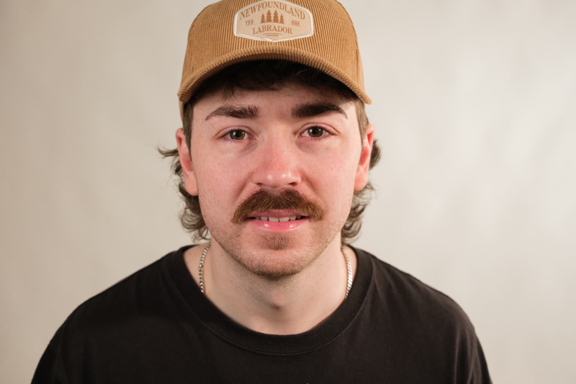 Studio headshot of Josh Janes in a tan Newfoundland Labrador cap