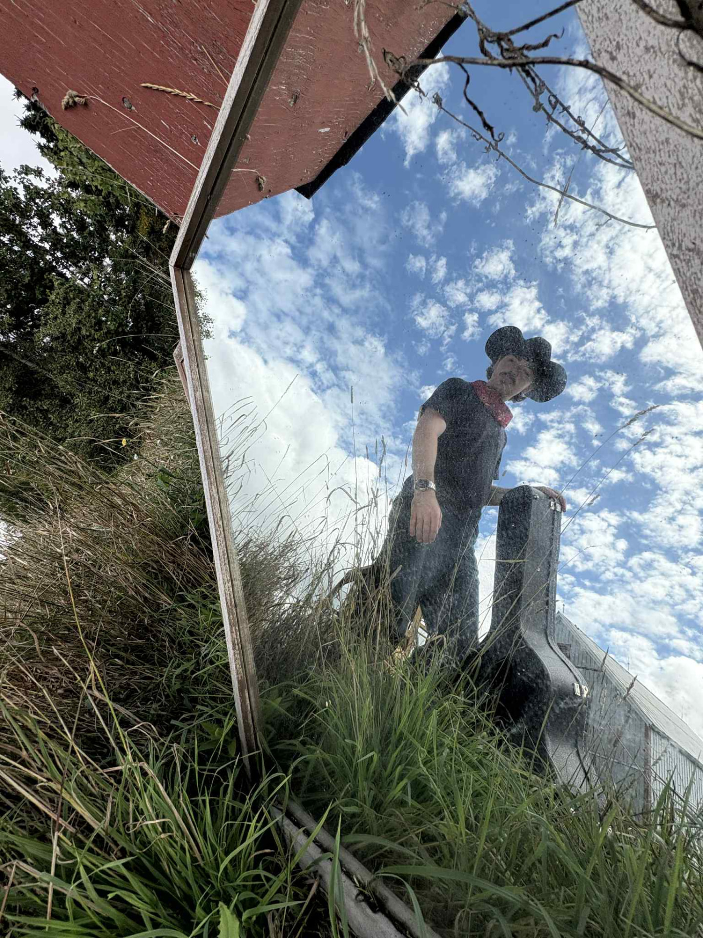 Josh Janes reflected in a mirror laid on the grass under a cloudy sky